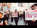 Protest in 2017 with signs that support Medicare for All, people marching in the street