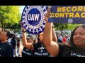 Four Black women march with t-shirts that say “Labor vs. Corporate Greed.” They’re holding UAW signs.