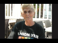 A smiling woman is pictured with short blond hair and a black Union Yes t-shirt with a rainbow on it.