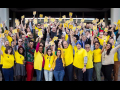 NewsGuild members standing together in yellow, smiling holding signs with arms up