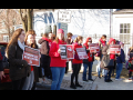 A crowd holding signs saying Support Somerville Educators and Living Wage for Paras