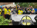 Young people of various races, fists in air, all masked. Some wear yellow "Gig Worker United" shirts and those in front hold a big banner with the group's logo and the initials of the Canadian postal union.