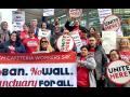 Workers in red UNITE HERE shirts and carrying round matching signs stand on steps outside. Those in front hold a large printed banner: "Tech Cafeteria Workers Say... No Ban, No Wall, Sanctuary for All."