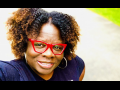 Close-up selfie of Petal Robertson, a Black woman with red glasses, smiling into the camera, outdoors