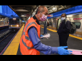 Man in orange vest hands out masks inside a train station