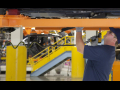 An autoworker tightens bolts on a car chassis above his head.