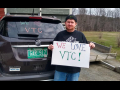 protester for VSCS Thrive! with a sign and his car that has a pro-VTU slogan on the back windshield