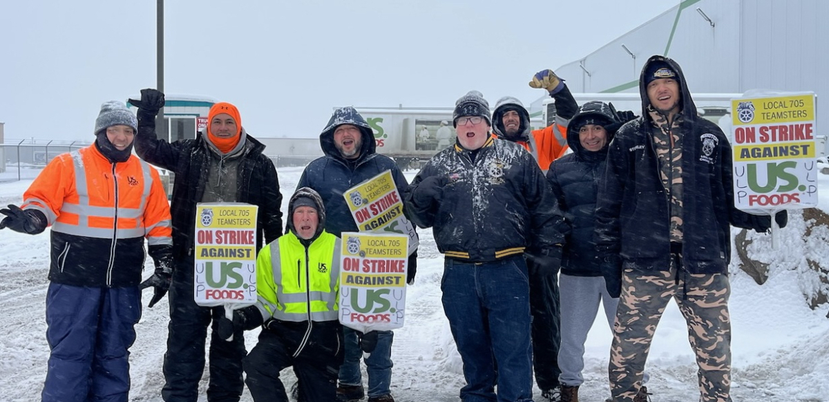 A group of workers stands in the snow and cold outside a US Foods yard in Spokane, Washington holding signs that say Local 705 Teamsters On Strike Against US Foods.