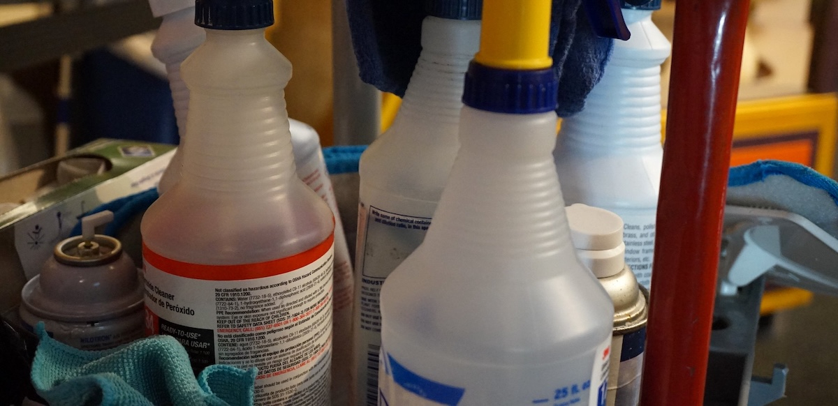 A closeup of bottles of cleaner in a custodial cart.
