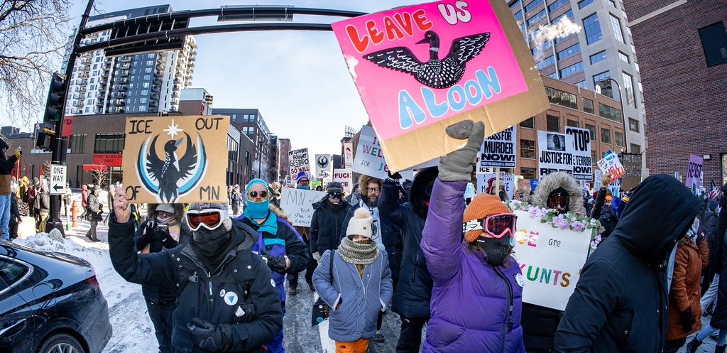 Marchers bundled against the cold carry colorful signs