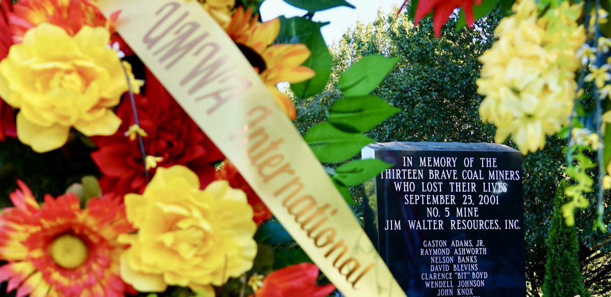 A wreath of flowers with a UMWA International sash around it sits in front of a monument to remember the 13 miners who lost their lives at the Jim Walter Resources No. 5 Mine in September 2001.