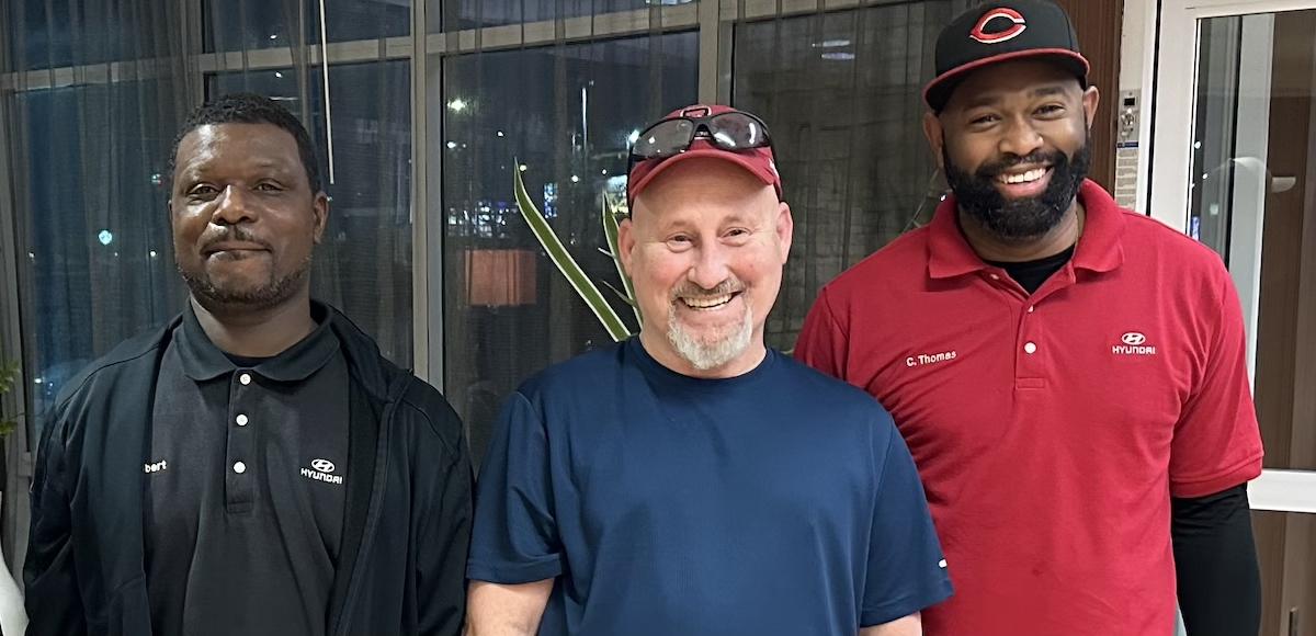 Three smiling men, two African American, one European American, face the camera