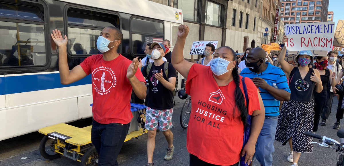 Marchers wearing masks walk through the streets of New York City, with Jabari Brisport and Marcela Mitaynes in the front.