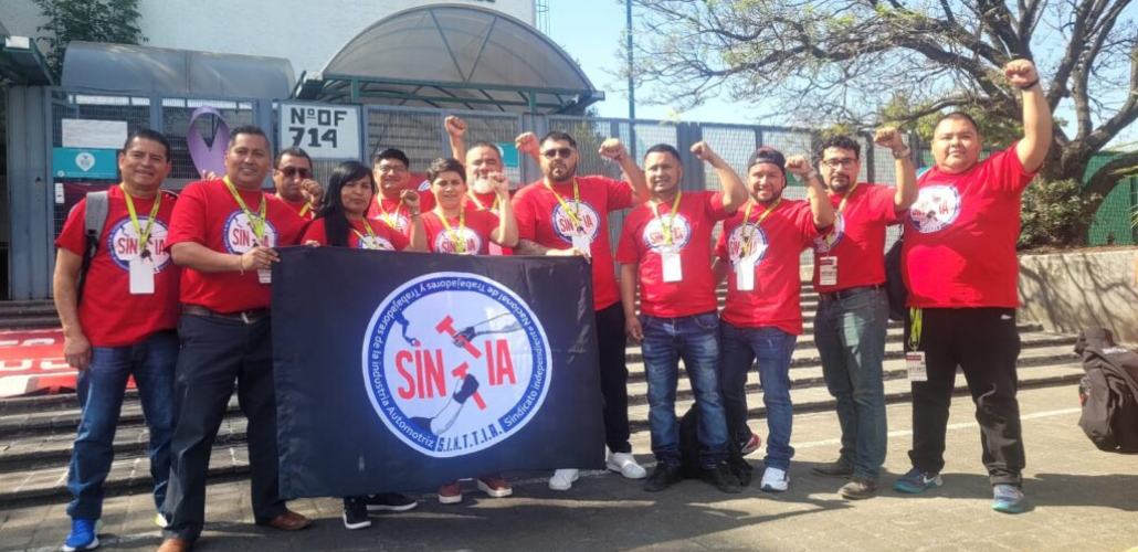 Miembros del comité de revisión salarial del SINTTIA posan con camisetas sindicales rojas y los puños en alto frente al Centro Federal de Conciliación y Registro Laboral.