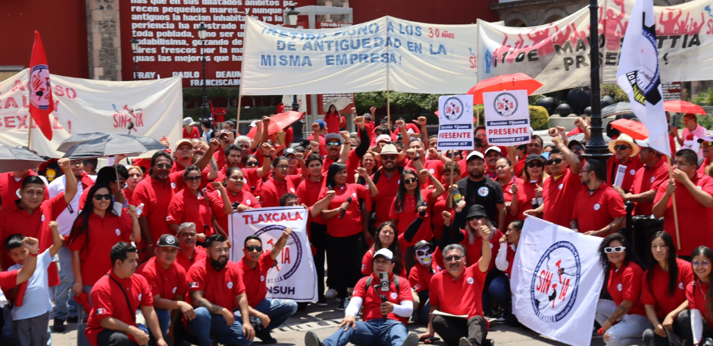 Una gran multitud de miembros de SINTTIA con camisetas rojas sostienen pancartas celebrando el Primero de Mayo.