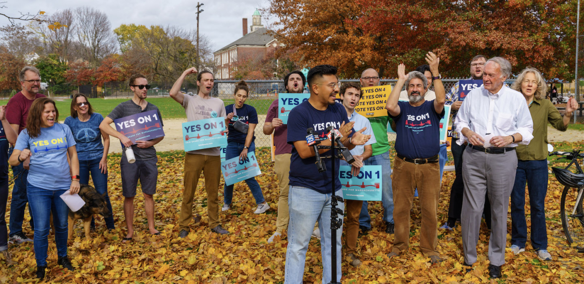Outside rally among fall leaves with twenty happy people with Yes on 1 signs and t-shirts
