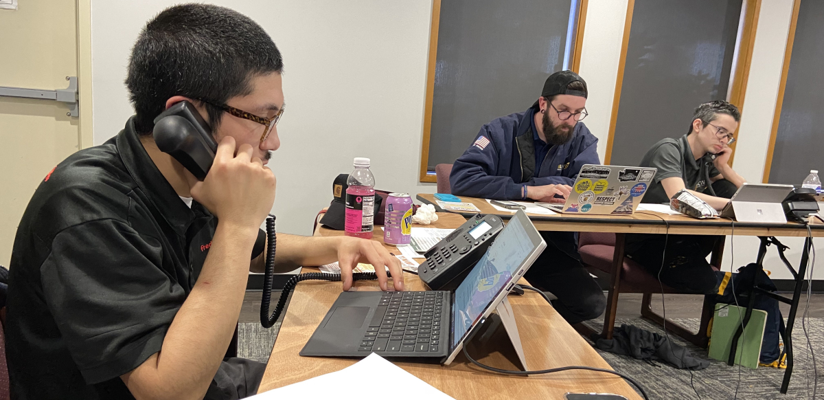 Three union activists sit around a table on their phones, making calls to drum up support for Initiative 1.