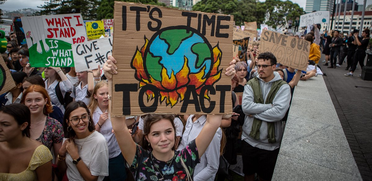 New Zealand students hold signs with slogans like "It's Time to Act," with a drawing of the earth being consumed by flames, during a school strike in March 2019.