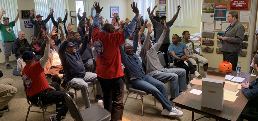 Strike authorization vote - people standing with arms raised.