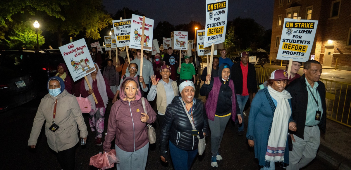 East African workers carrying signs march in the dark during the strike.