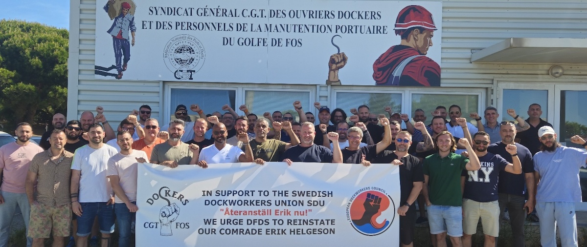 A group of workers hold a banner in front of a French banner.