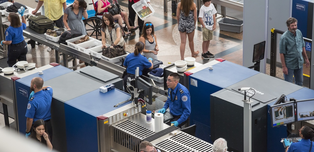 TSA workers are shown screening bags and scanning passengers at an airport