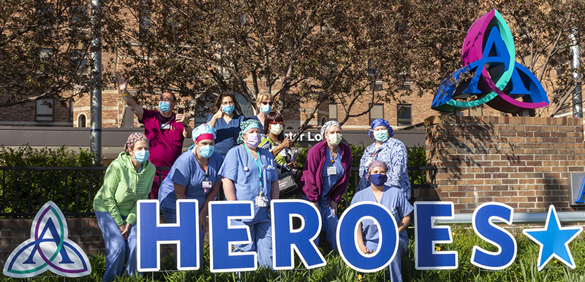 Medial personnel gathered outside in back of a sign that says "Heroes."