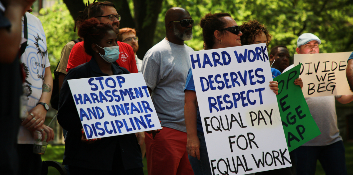 Housekeepers at the University of Pennsylvania rally holding signs that say "Hard work deserves respect: equal pay for equal work."