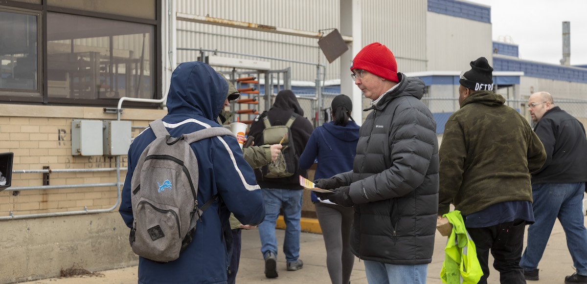 Candidate Shawn Fain passes out leaflets to several workers entering parts plant