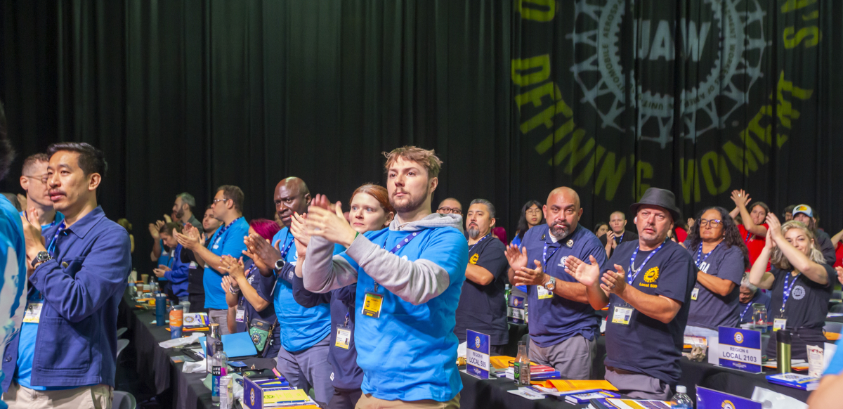 Delegates stand and applaud at the UAW convention.