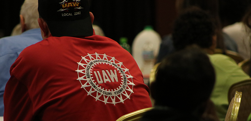 Back of man in red UAW shirt seated at event.