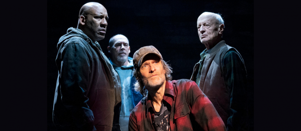 Four actors on stage in front of a black background.