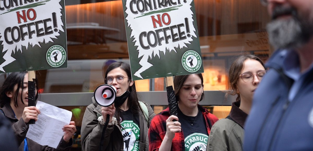 workers march with “no contract, no coffee” signs, one with a megaphone