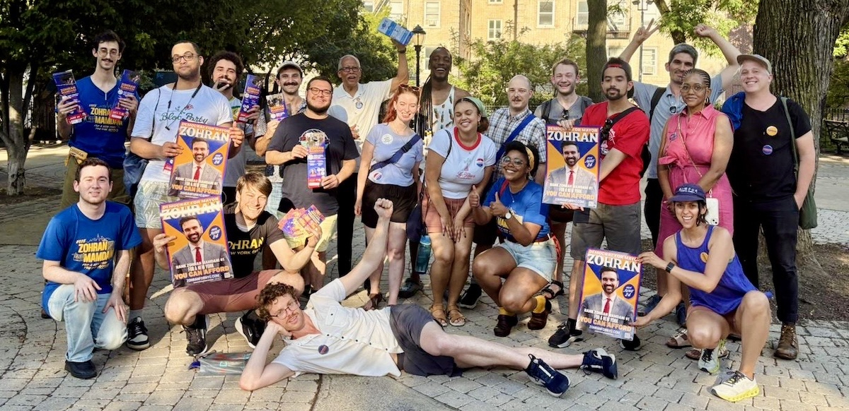 A group of around 30 canvassers pose with signs and fliers.