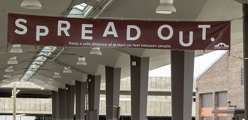 SPREAD OUT written on a sign above a road with pillars in the background.