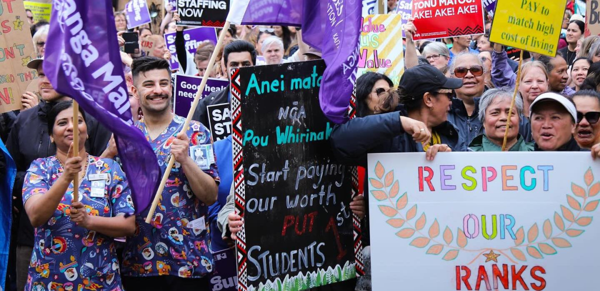 Workers rally holding colorful banners and signs.