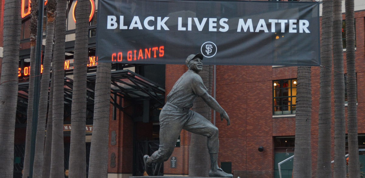 A Black Lives Matter banner hangs behind a statue of Willie Mays at Oracle Park.