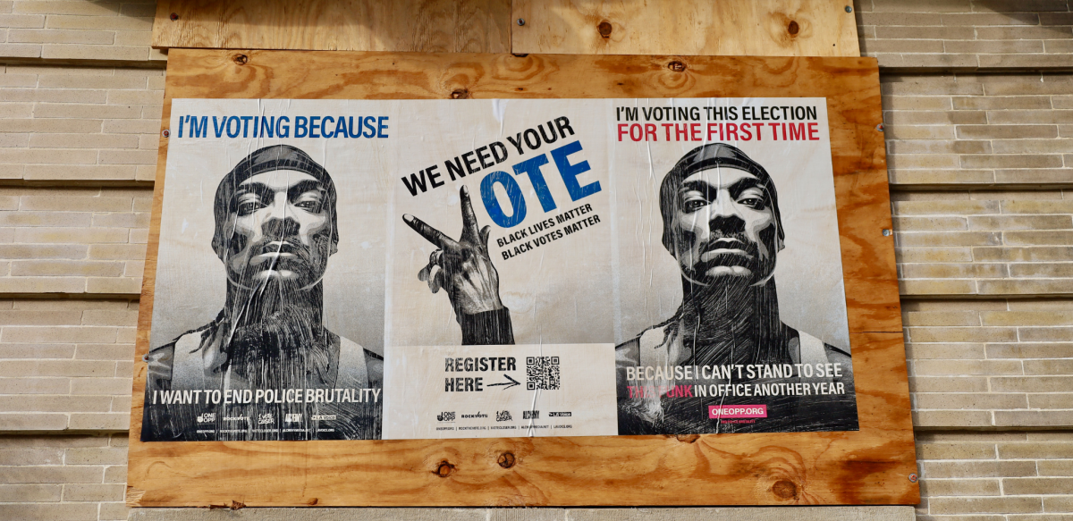 On a boarded up section of a brick wall, three posters. The outer two show Snoop Dogg's face, and the middle one shows a hand making a "V" gesture. Text of the 3 posters: 1. "I'm voting because I want to end police brutality." 2. "We need your vote. Black lives matter. Black votes matter. Register here. [QR code.]" 3. "I'm voting this election for the first time because I can't stand to see that punk in office another year." 