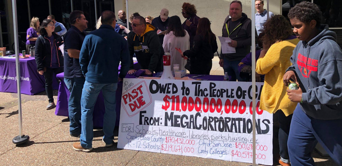 Supporters of Prop 15 tabling for the measure with a big sign.