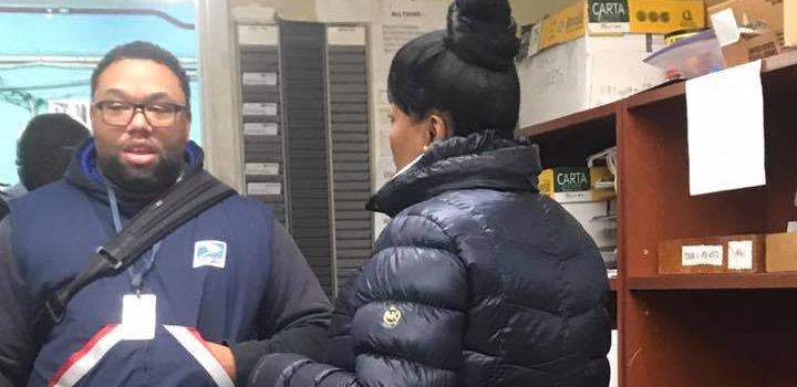 Two postal workers talking to each other inside an office.