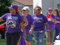 A group of black and white workers wearing purple SEIU T-shirts march.