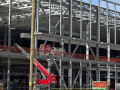 Metal ribs and girders of a factory being constructed are visible, with a red construction crane