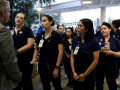 A group of nurses in dark blue scrubs with badges confront a man in a grey suit who is blocking their path.