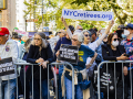 a line of retirees protest behind a metal barrier