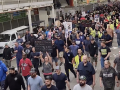 Hundreds march though an industrial plant, one sign reads: Historic Slap in Our Faces