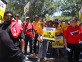 One Black man and several Asian and Latina women hold strike signs in a hotel parking lot.