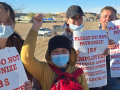 Four strikers holding signs, one with a fist in the air, face the camera.