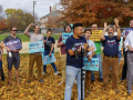 Outside rally among fall leaves with twenty happy people with Yes on 1 signs and t-shirts