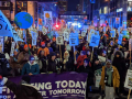 Crowd of climate strikers at night with signs and flags and a banner in downtown Minneapolis.