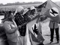 Seven women stand by a car holding a Farmworkers Union flag
